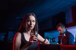 young alcoholic woman drinks a cocktail at a bar 
