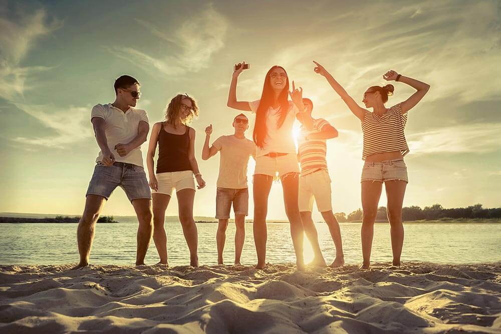 lighthousetreatment-what-do-i-do-all-summer-now-that-im-sober-article-photo-friends-funny-dance-on-the-beach-under-sunset-sunlight-437151931