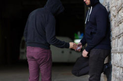 two men in hoodies dealing with drugs on the streets