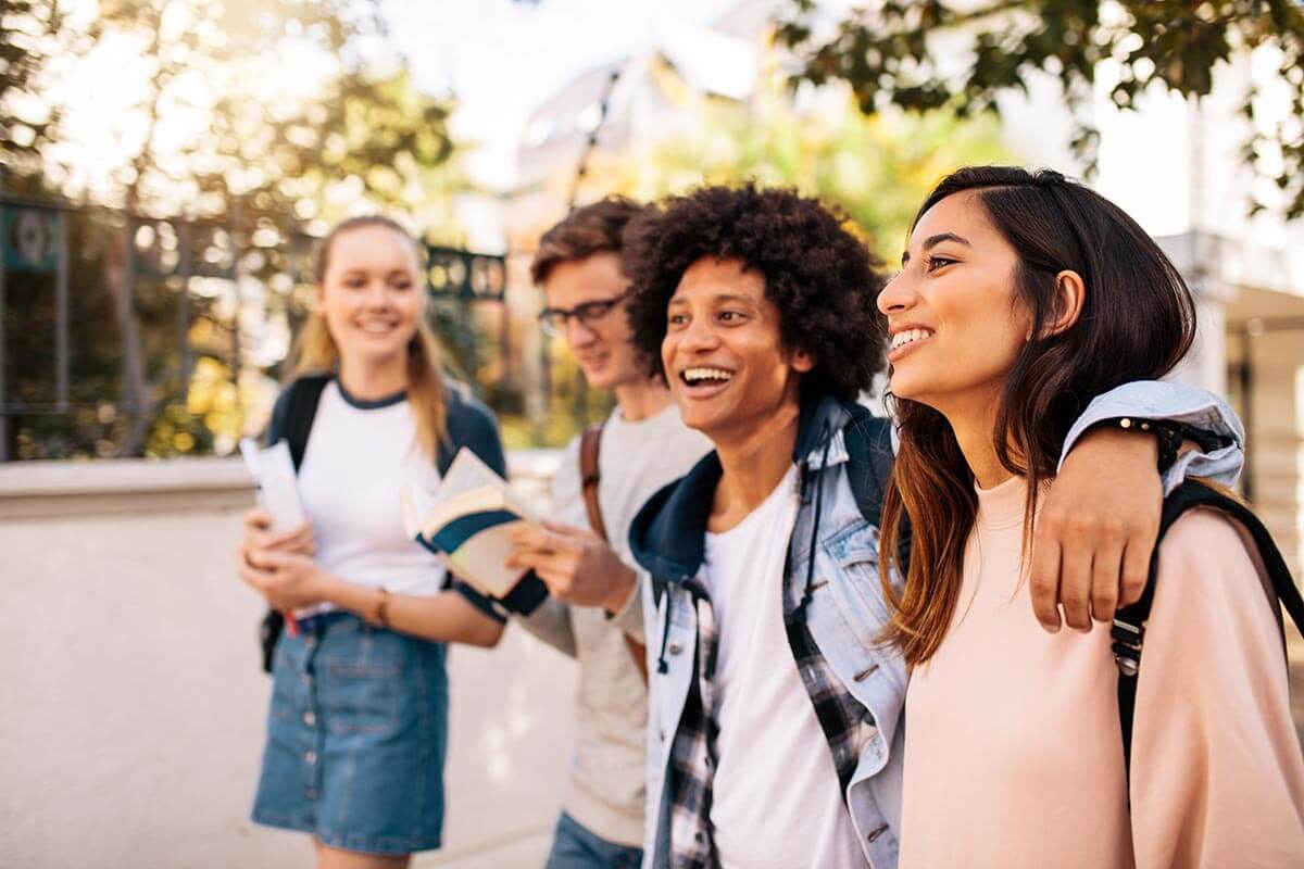 lighthousetreatment--the-tools-you-need-to-stay-sober-in-college-article-photo-college-students-walking-together-outdoors-group-of-young-people-in-college-campus-674439163