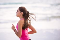 a woman running by the beach to fulfill her New Year's resolution to be fit